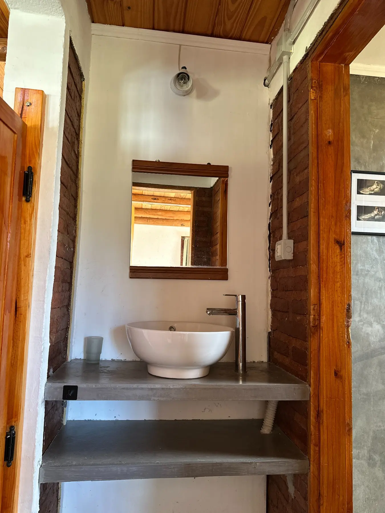 Baño con bacha blanca y estantes de piedra