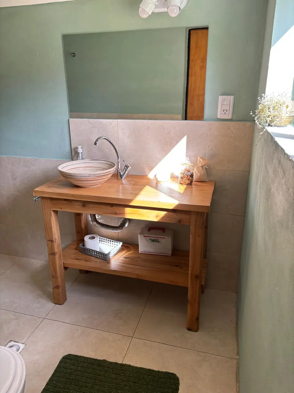 Baño equipado con mesada de madera y detalles verdes